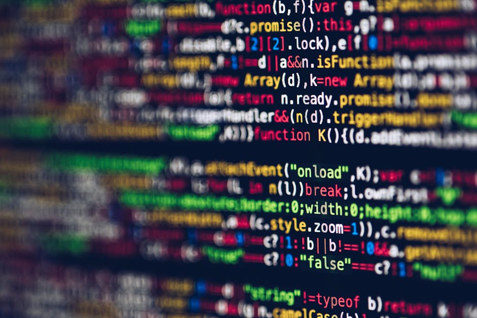 A person with light skin is using a black laptop on a dark table, focusing on the screen which displays lines of code with syntax highlighting, suggesting programming or software development activity.